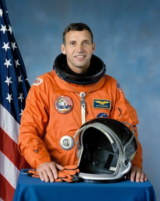 David Hilmers, Colonel, USMC, Retired.

Astronaut in orange space suite 